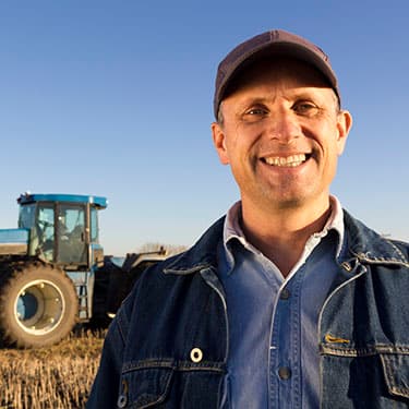 Happy Farmer standing in a field in front of his tractor